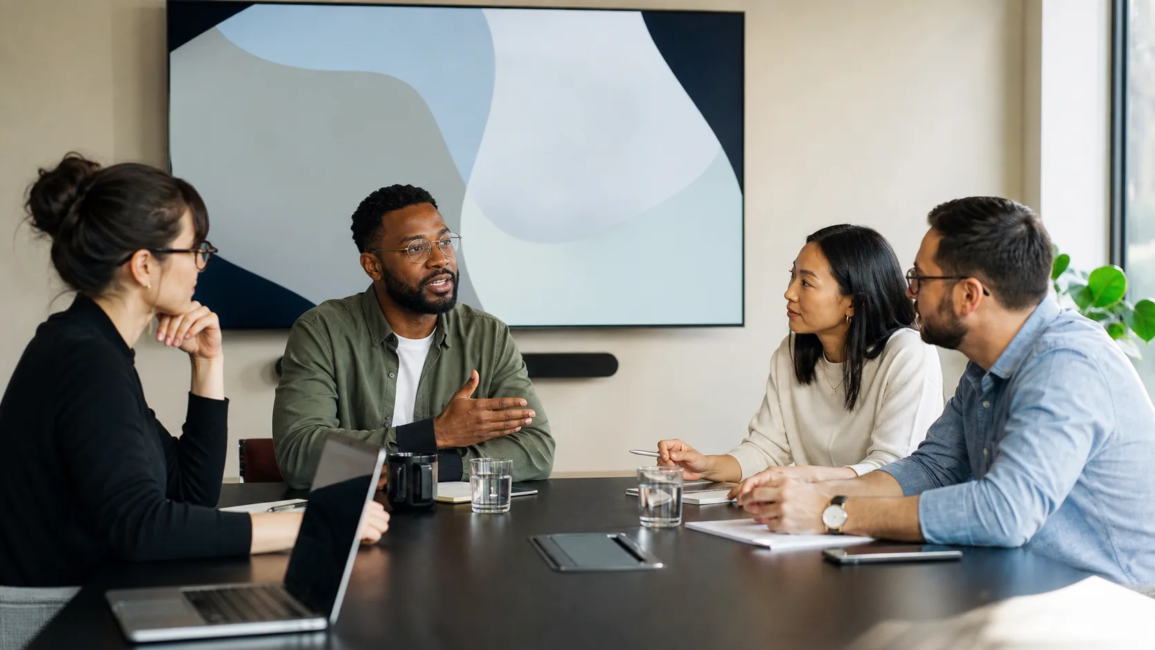Meeting facilitator guiding a team discussion around a conference table
